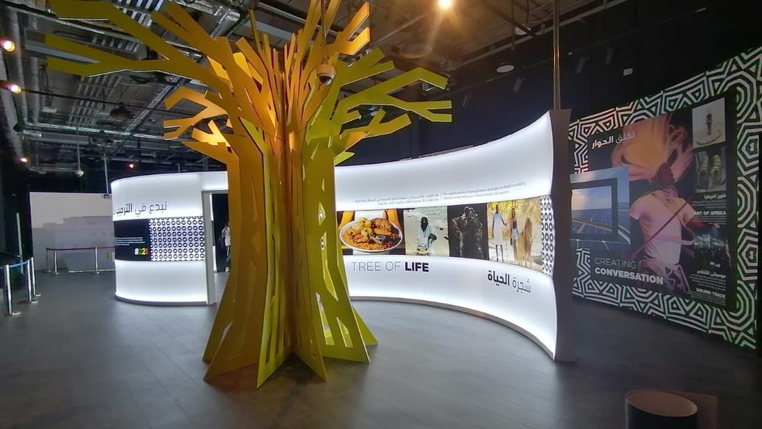 Fabricated tree sculpture in front of a curved illuminated wall