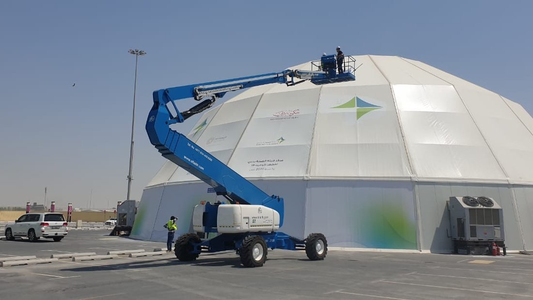 Boom lift crew installing printed branding panels on a large dome tent