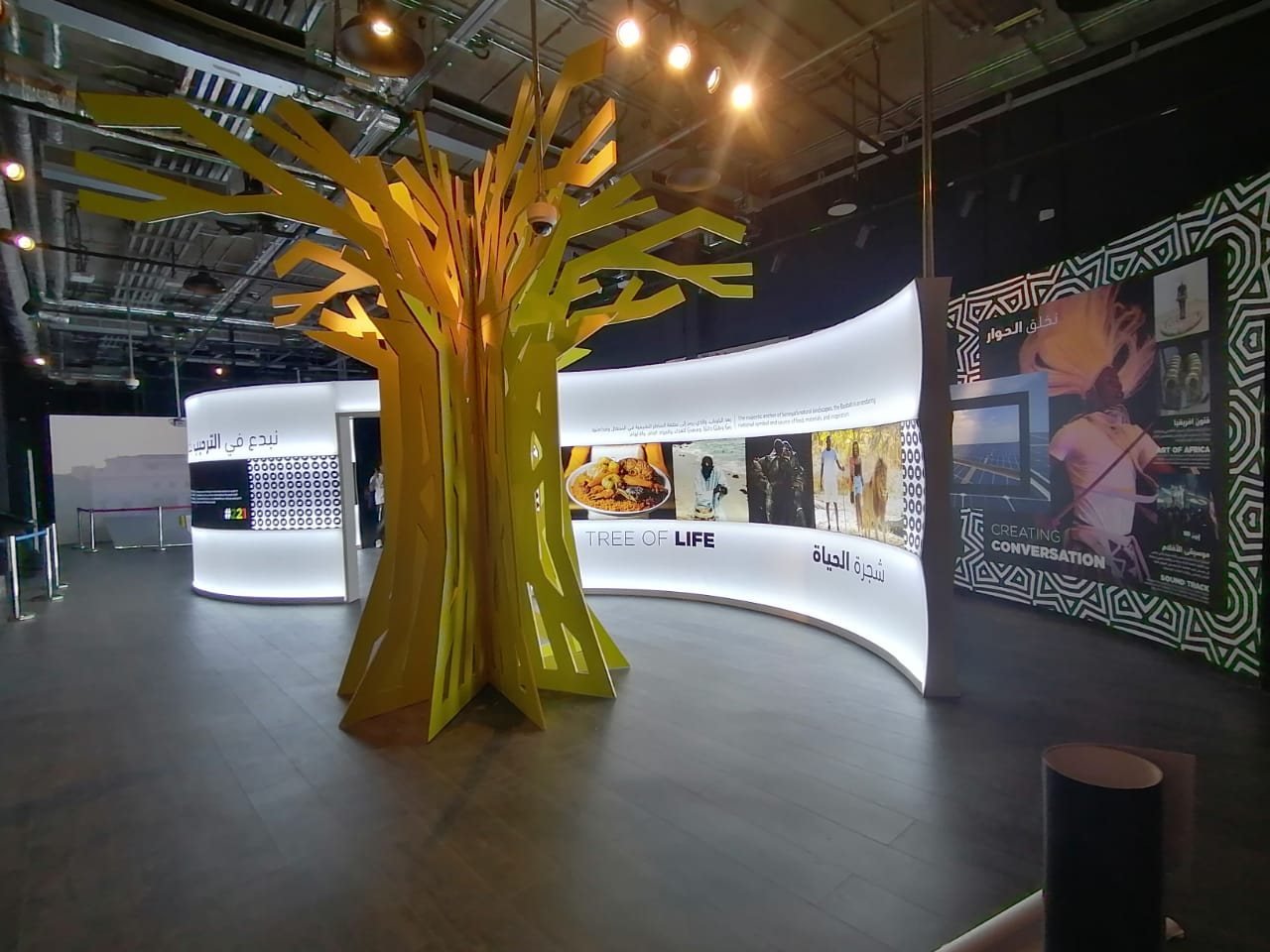 Fabricated tree sculpture in front of a curved illuminated lightbox